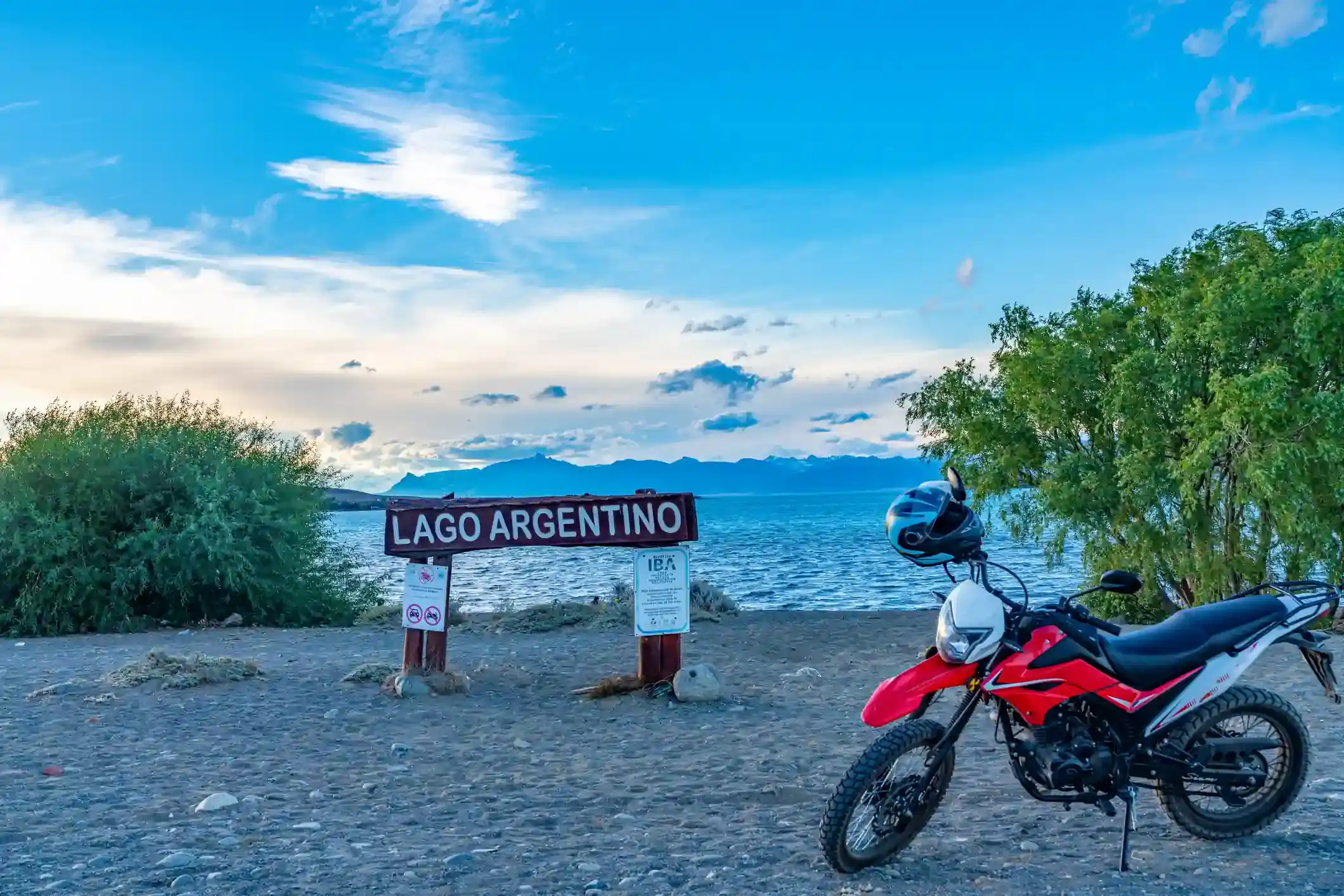A motorcycle parked by the Lago Argentino sign on the shore near El Calafate
