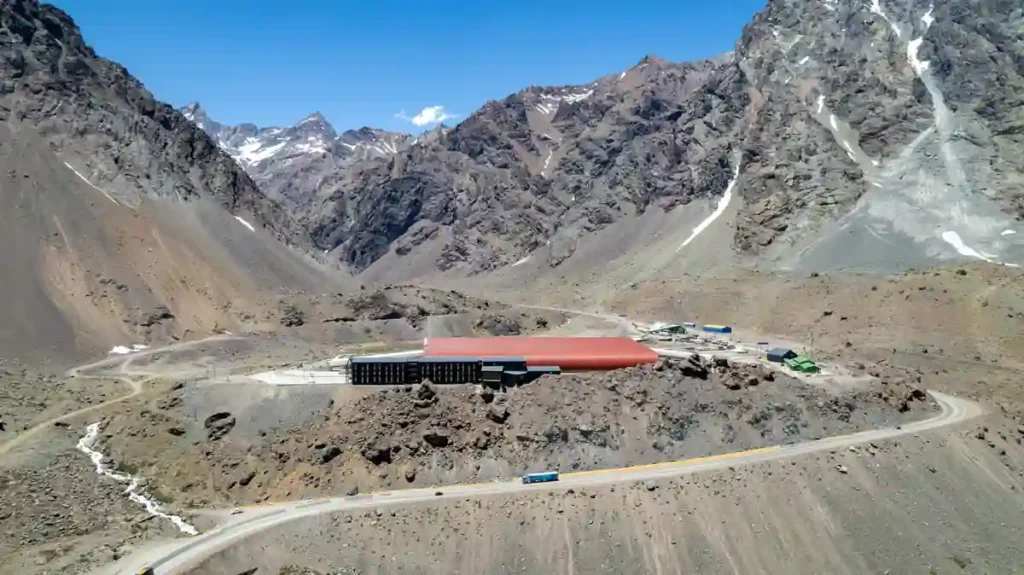 Aerial view of a border control complex with a long red roof in a high Andean valley on the Argentina-Chile crossing corridor.